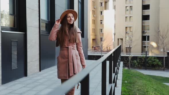 Woman in a coat and hat walking the stairs of the office building background