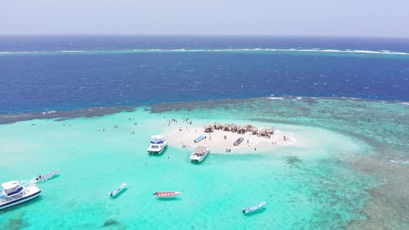 Tourists on paradise island tour of idyllic coral islet, Cayo Arena; aerial