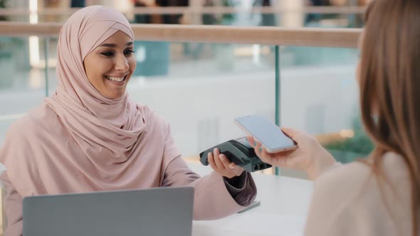 Friendly Muslim Woman in Hijab Seller Agent Offers Pay for Service Through Bank Terminal Girl