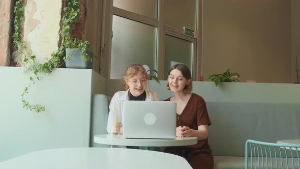 Young Girls Work Remotely in a Cafe on the Summer Terrace