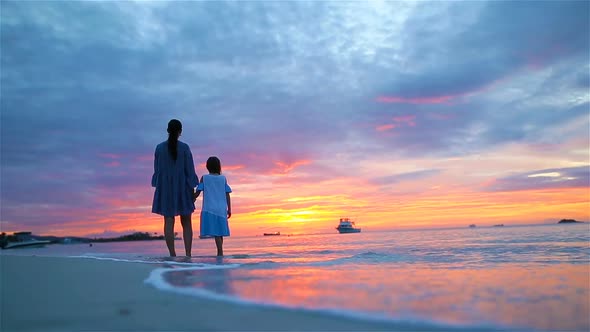 Little Girl and Happy Mother Silhouette in the Beautiful Sunset at the Beach. Amazing Colors on the