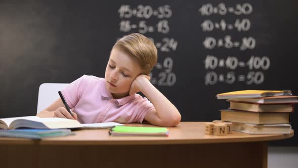 Relaxed Bored Schoolboy Sitting at Desk, Unwilling to Prepare Math Homework