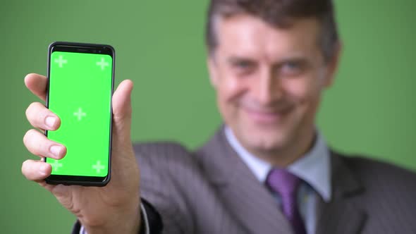 Mature Handsome Businessman Against Green Background