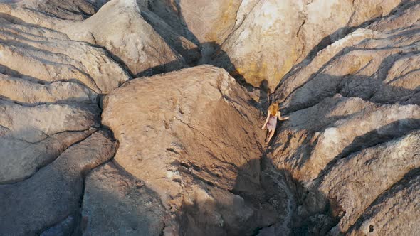 Aerial View of a Girl Who Climbs the Red Mountains in a Dress