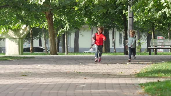 Young Happy Girl Running It Park with Her Sister Together. Slow Motion