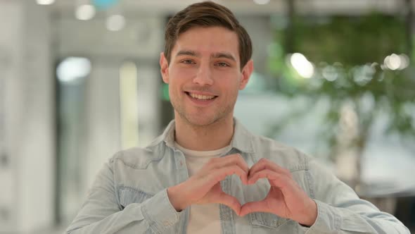 Portrait of Creative Young Man Showing Heart Sign By Hand