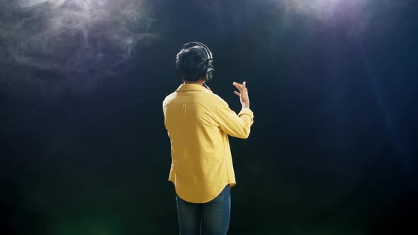 Back View Of A Young Boy With Headphone Holding A Microphone And Singing On Black Background