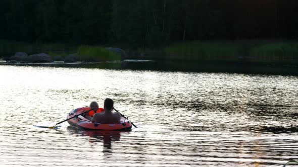 Happy laughing four year old girl rowing with her dad on calm lake on a summer evening, STATIC SLOW