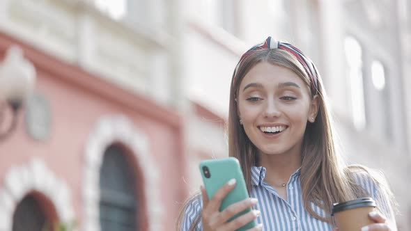 Cute Woman Wearing in Blue and White Striped Dress Using App on Smartphone Walking on the Old City