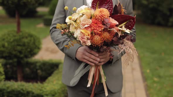 Groom Goes Down the Alley Between Bushes with a Wedding Bouquet to His Beloved Bride First Meeting