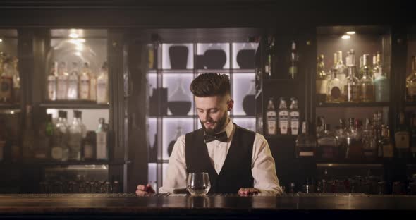 The Bartender Is Taking a Glass From the Shelf and Pouring a Drink Into the Glass. 