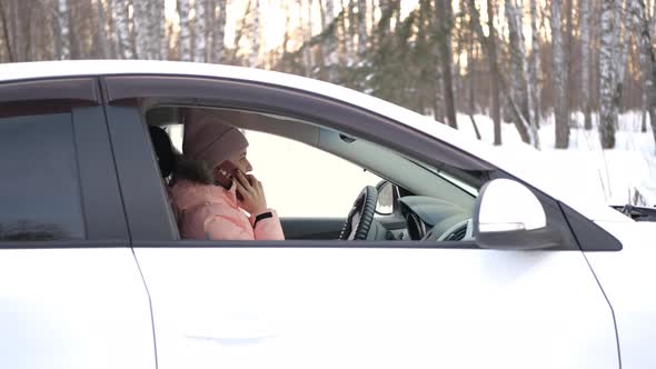 Young Woman Talking on Phone Inside Car in Winter