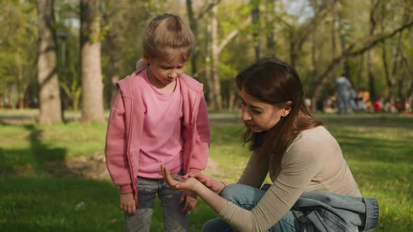 Mother Shows Butterfly to Little Daughter in Spring Park