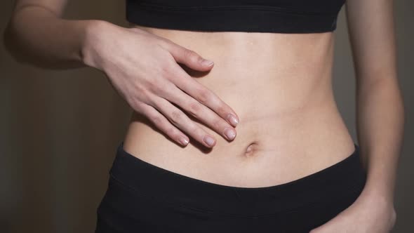 Close Up. Woman Applying Moisturizer Cream on Her Belly. Young Girl Smears Cream Her Beautiful