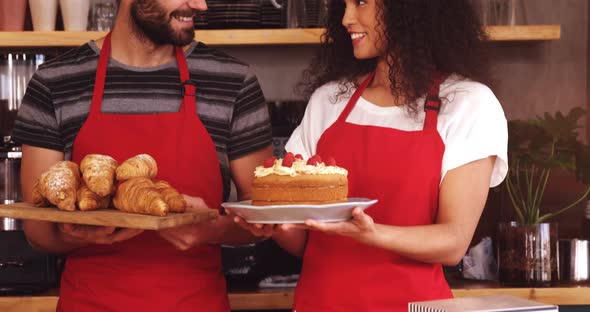 Waiter and waitress holding a tray of croissants and cake