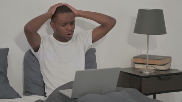 African Man Reacting to Loss on Laptop in Bed