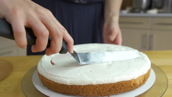 Close up of woman hands making sweet cake with white cream and biscuit.