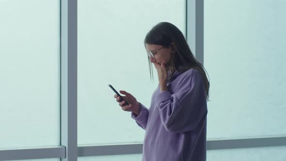 Stressed Woman Standing With Phone in Hands Looking at Phone Screen