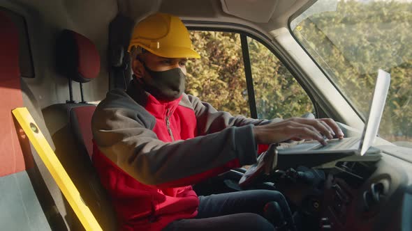 Man with Helmet and Face Mask Using Tablet and Leveler Tool in the Van