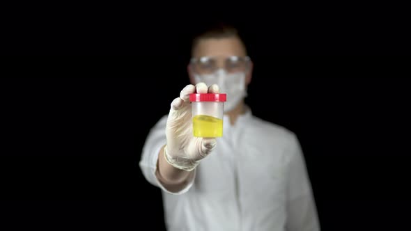 Urine in a Test Bank Close-up, Man Doctor Holds Out a Can of Urine To the Camera on a Black