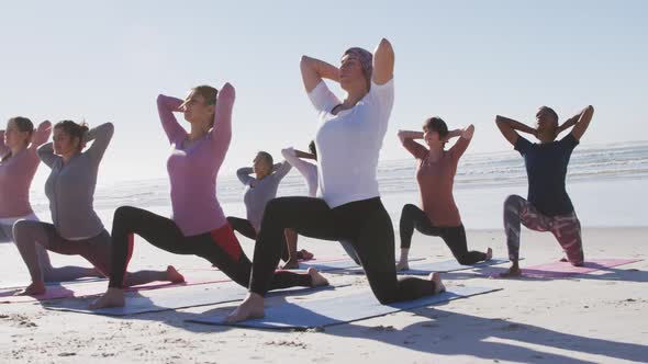 Multi-ethnic group of women doing yoga position on the beach and blue sky background