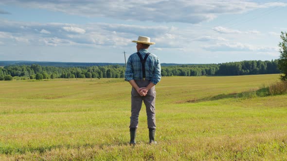 Farmer Standing in Mown Field Looking Far Ahead