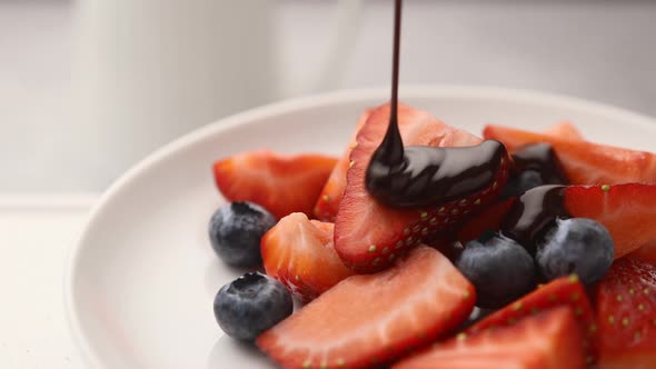 Fresh sliced strawberries and blueberries, poured with melted chocolate