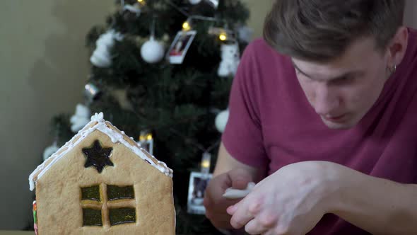 A Guy Decorates a Christmas Gingerbread House