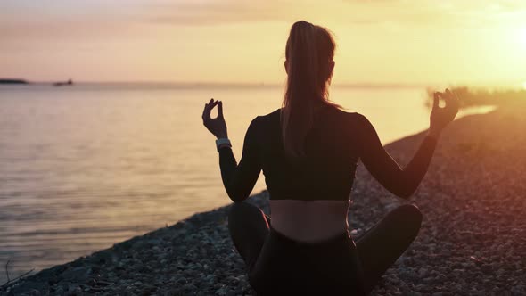 Pleasant Woman Sitting in Lotus Position Meditating at Sunset Beach