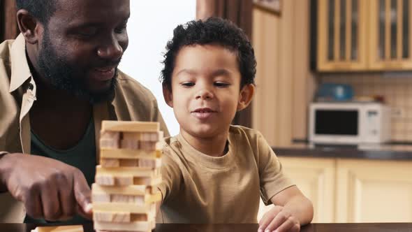 African American dad sitting near his child and playing Jenga