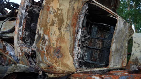 Burnt Down Car Leftovers Lying on Side in Summer Forest in Ukraine