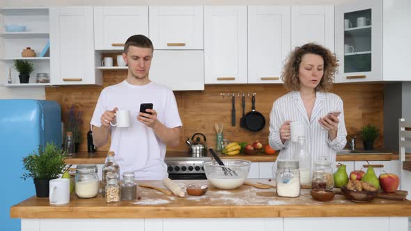 Millennial Couple Obsessed With Smartphones Ignoring Each Other On Kitchen