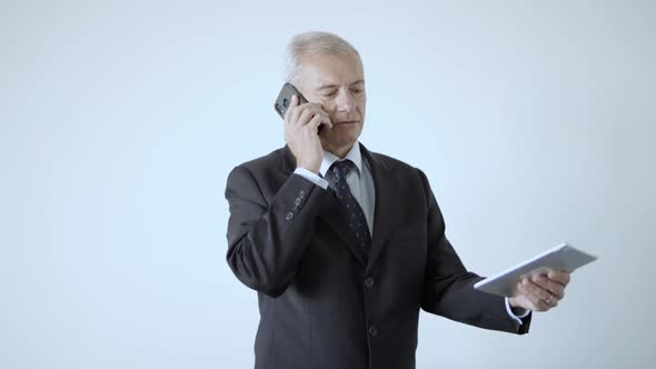 Serious Grey Haired Businessman in Suit and Tie Holding Tablet