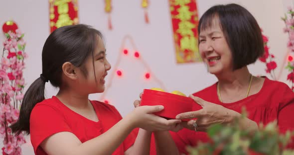 Happy Asian Girl Giving Her Grandmother Orange for Chinese New Year Blessing Gift.