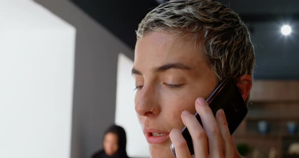 Executive talking on mobile phone while colleague discussing in background 4k