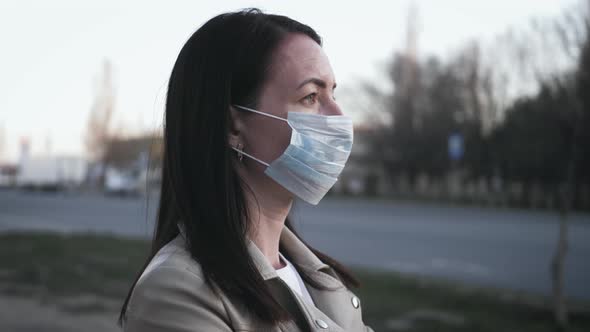 Young Woman in a Medical Mask for Protection From the Epidemic on the Street in the City. Concept