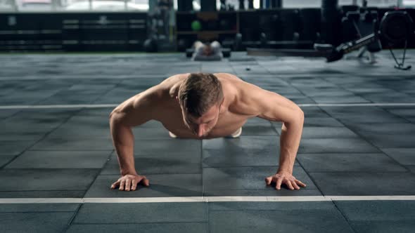 Young male athlete trains in the gym, push-ups from the floor, crossfit, endurance training