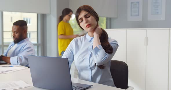 Beautiful Woman Suffering From Neck Pain in Office