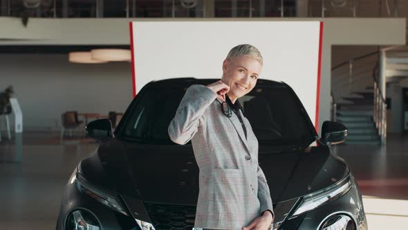 Beautiful Woman is Holding a Key While Standing Near the New Car in Car