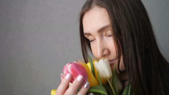 Happy Girl Sniffing a Bouquet of Tulips and Smiling