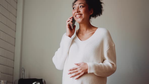 Smiling African pregnant woman talking by phone