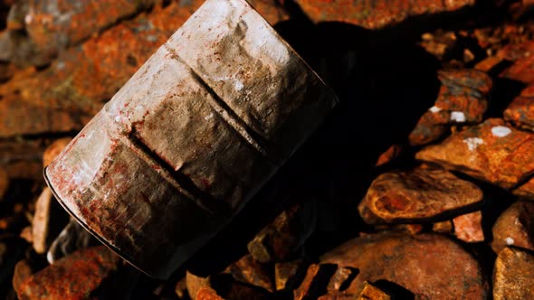 Rusty Destroyed Metal Barrel on Beach Rocks