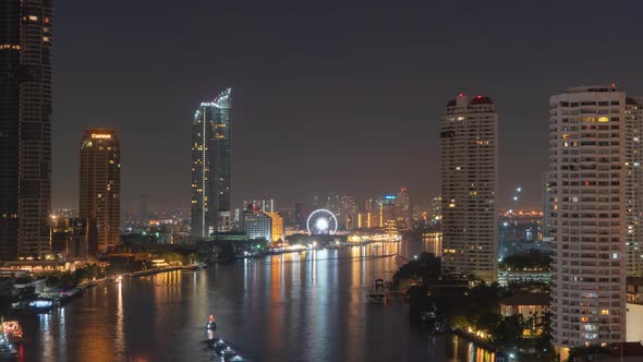 Time lapse of ferris wheel by Chao Phraya River in financial district and skyscraper buildings