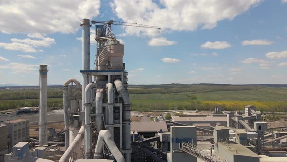 Aerial view of cement plant with high concrete factory structure and tower crane at industrial