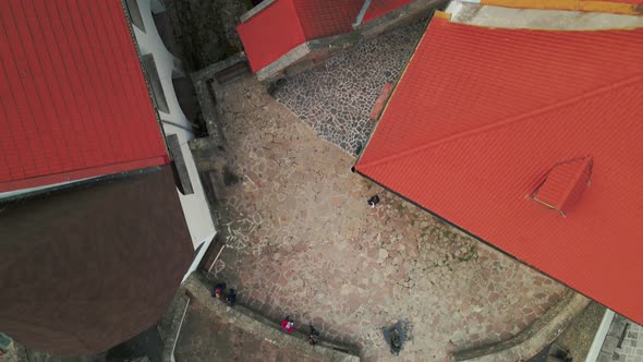 Aerial top down view of medieval castle on mountain in small european city at cloudy autumn day