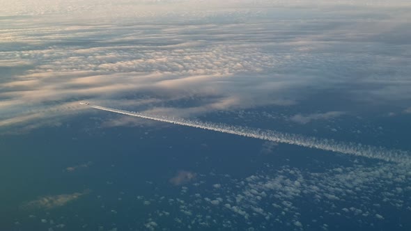 Incredible view from the cockpit of an airplane flying high above the clouds leaving a long white co