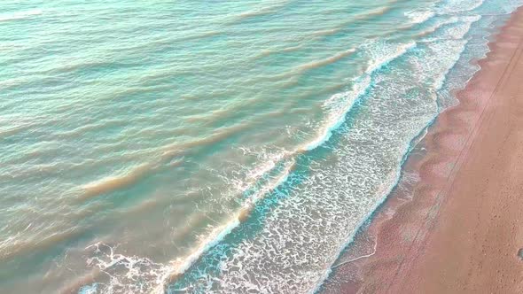 Drone view of the beautiful waves on the sandy beach,
