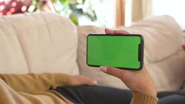 Close-up shot of green screen template smartphone in female hands at home