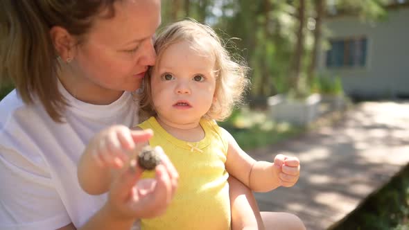 Little Cute Baby Toddler Girl Blonde with Curls on Mother's Arms