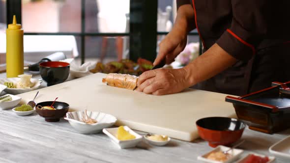 Hands Cutting Sushi with Knife.